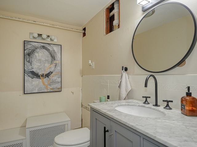 bathroom with vanity, toilet, radiator, and tile walls