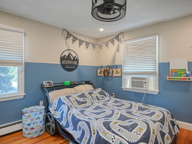 bedroom with cooling unit, hardwood / wood-style flooring, and a baseboard radiator