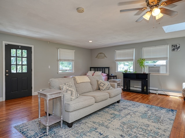 living room featuring a baseboard radiator, a skylight, hardwood / wood-style flooring, and plenty of natural light