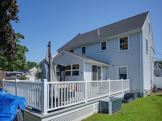 back of property with a wooden deck and a lawn