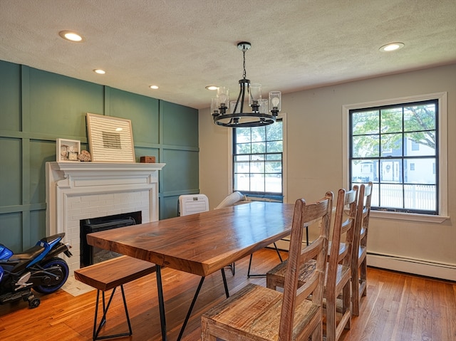 dining area with a notable chandelier, a textured ceiling, light hardwood / wood-style flooring, and a fireplace