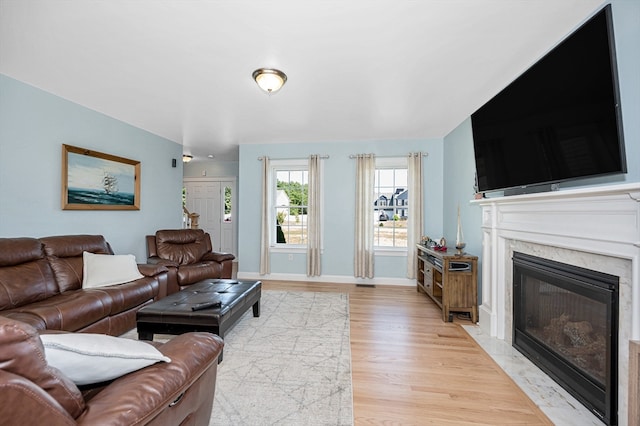 living room featuring a high end fireplace and light hardwood / wood-style floors