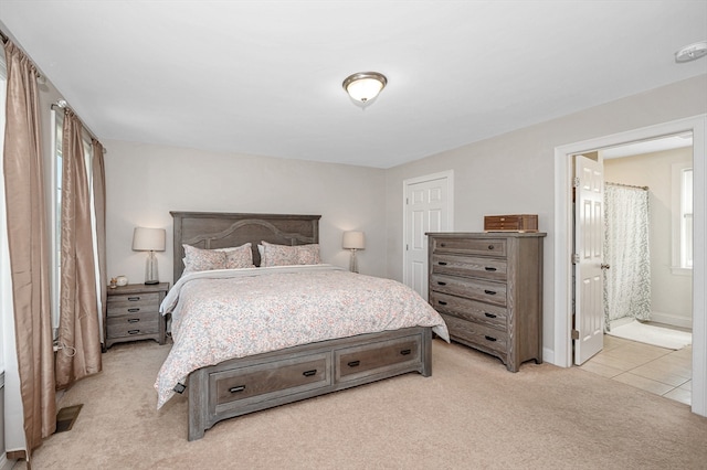 bedroom featuring light colored carpet and ensuite bathroom