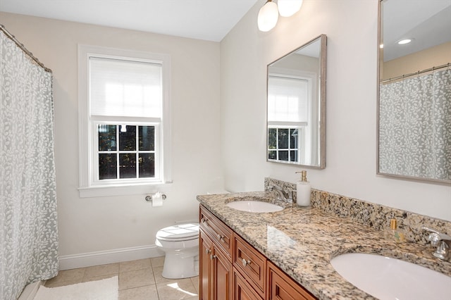 bathroom with vanity, toilet, a healthy amount of sunlight, and tile patterned flooring