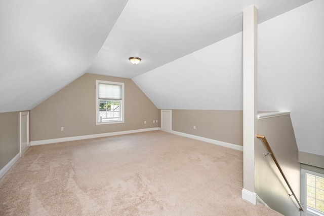 additional living space featuring light carpet and vaulted ceiling