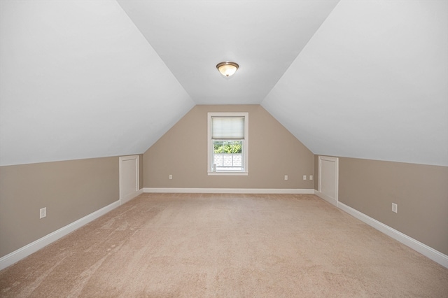 additional living space featuring light colored carpet and vaulted ceiling