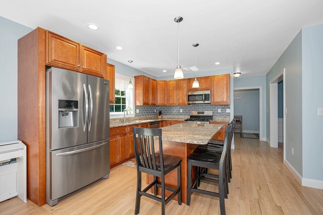 kitchen featuring a kitchen island, light stone counters, light hardwood / wood-style flooring, and appliances with stainless steel finishes