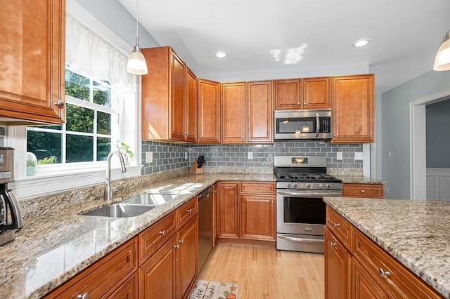 kitchen featuring light hardwood / wood-style flooring, backsplash, light stone counters, sink, and appliances with stainless steel finishes