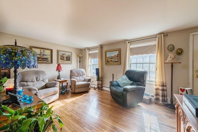 living room featuring a baseboard heating unit, plenty of natural light, and light wood-style flooring