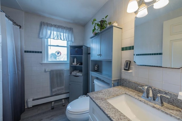 full bathroom with toilet, a baseboard heating unit, wood finished floors, vanity, and tile walls