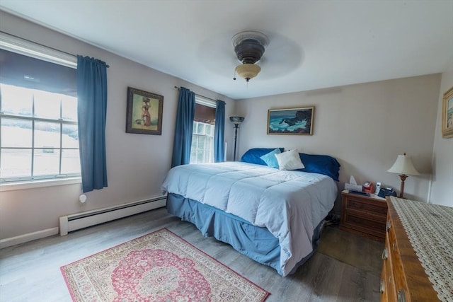 bedroom with a baseboard radiator, baseboards, ceiling fan, and wood finished floors