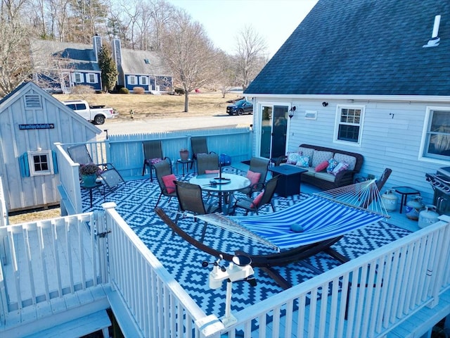 wooden terrace with an outbuilding, a patio, fence, and an outdoor living space