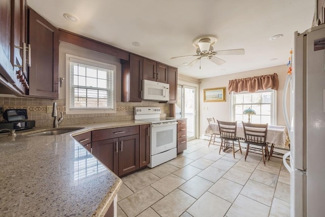 kitchen with tasteful backsplash, a sink, ceiling fan, light stone countertops, and white appliances