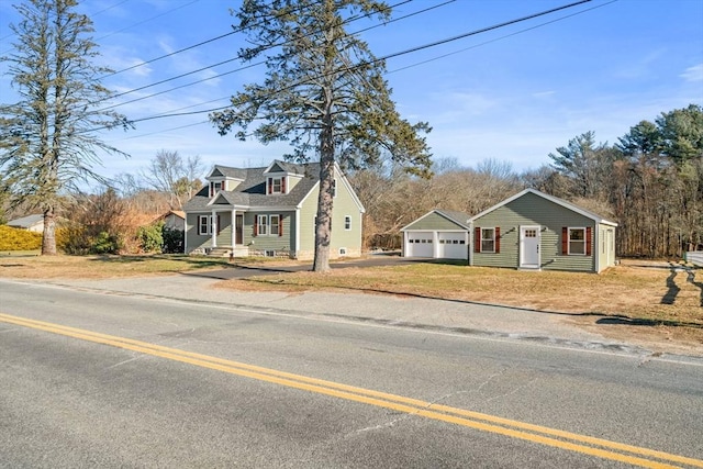 new england style home featuring a front yard, a garage, and an outdoor structure