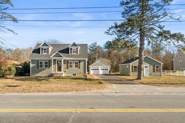 cape cod-style house featuring a front yard, a garage, and an outbuilding