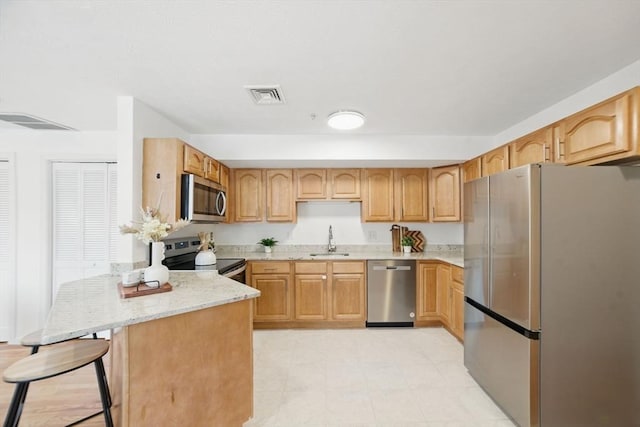 7 Conant Rd Unit 23, Winchester, MA 01890 - kitchen with stainless steel appliances, a sink, light stone countertops, a peninsula, and a breakfast bar