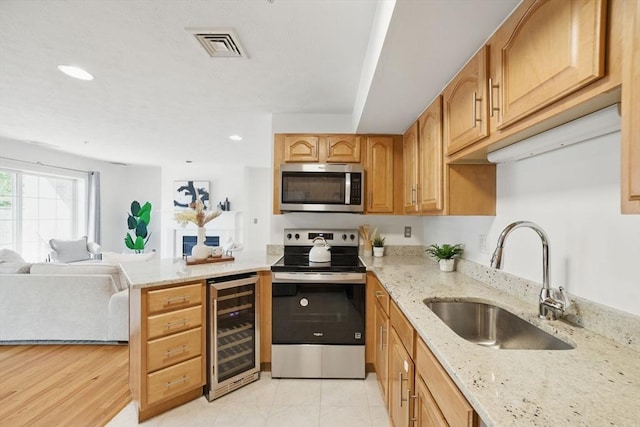 7 Conant Rd Unit 23, Winchester, MA 01890 - kitchen featuring appliances with stainless steel finishes, wine cooler, a sink, open floor plan, and light stone countertops