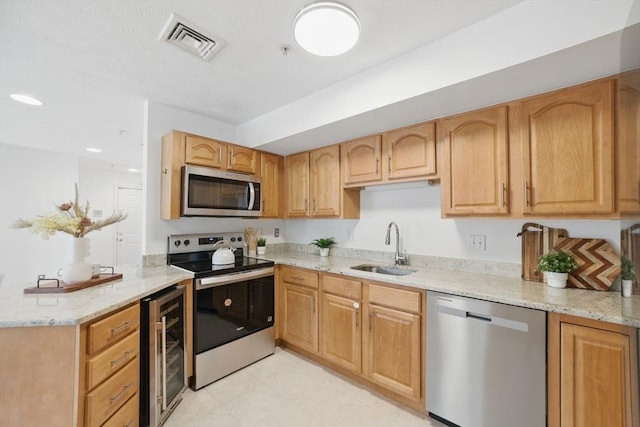 7 Conant Rd Unit 23, Winchester, MA 01890 - kitchen featuring appliances with stainless steel finishes, wine cooler, a sink, light stone counters, and a peninsula
