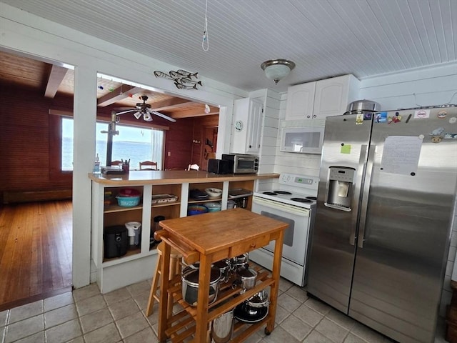 kitchen featuring white cabinets, light tile patterned floors, white appliances, and wood walls