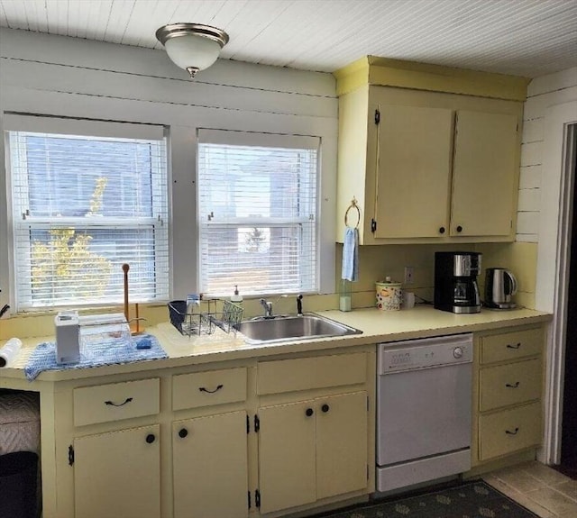 kitchen with wooden walls, dishwasher, cream cabinetry, and sink