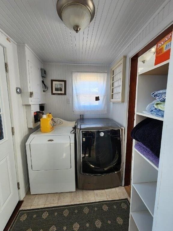 washroom featuring independent washer and dryer, light tile patterned floors, and wooden walls