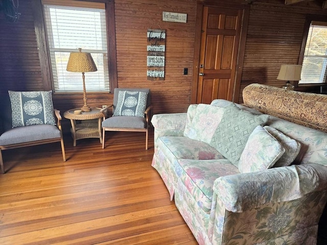 living room with light hardwood / wood-style flooring, plenty of natural light, and wooden walls