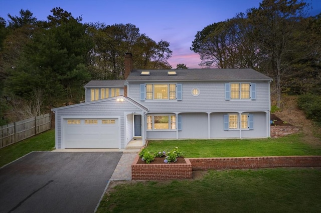 view of front of home featuring a garage, a chimney, and asphalt driveway