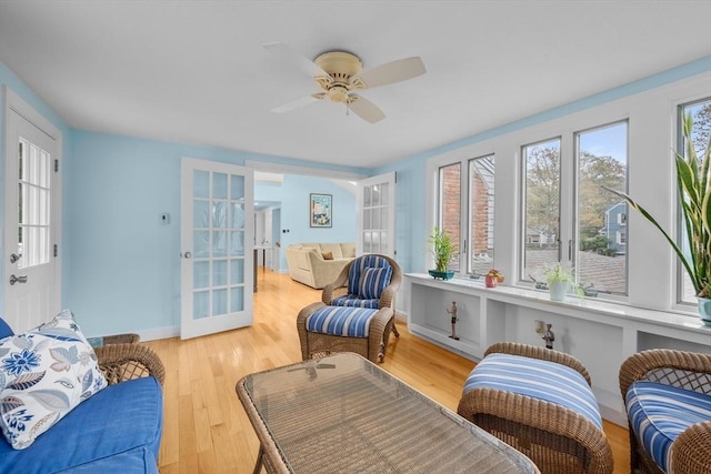 sitting room featuring french doors, a ceiling fan, wood finished floors, and baseboards