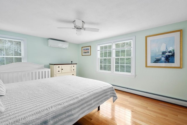 bedroom with a wall mounted AC, a baseboard radiator, multiple windows, and wood finished floors