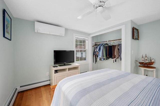 bedroom featuring an AC wall unit, a baseboard radiator, a closet, and light wood-type flooring