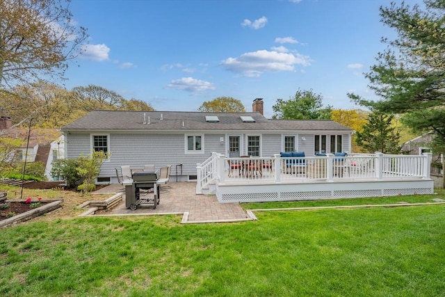 back of property with a patio, a chimney, a lawn, and a wooden deck