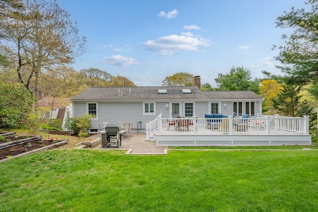 rear view of house with a yard, a chimney, a deck, and a patio