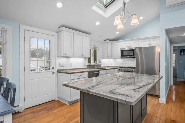 kitchen featuring appliances with stainless steel finishes, a sink, healthy amount of natural light, a skylight, and lofted ceiling