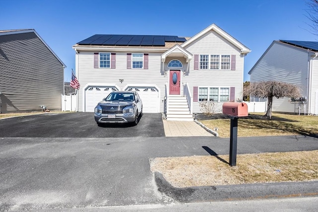 raised ranch with driveway, a standing seam roof, metal roof, a garage, and solar panels