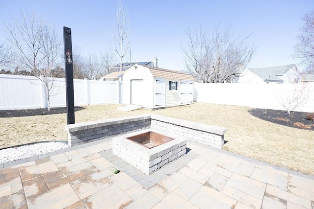 view of patio / terrace featuring a storage shed, an outdoor structure, a fenced backyard, and an outdoor fire pit