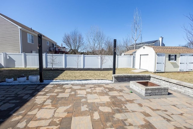 view of patio featuring an outbuilding, a fenced backyard, a shed, and an outdoor fire pit