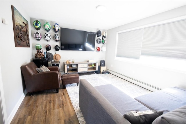 living room featuring a baseboard heating unit, baseboards, and wood finished floors