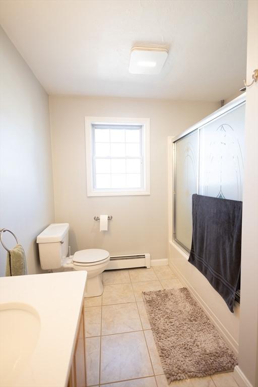 full bathroom with vanity, a baseboard radiator, tile patterned flooring, toilet, and combined bath / shower with glass door