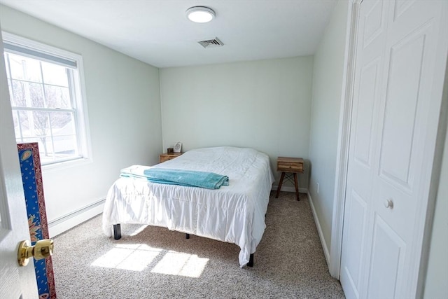 carpeted bedroom featuring a baseboard radiator, baseboards, and visible vents