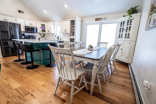 dining area with visible vents, a baseboard radiator, recessed lighting, vaulted ceiling, and light wood-type flooring