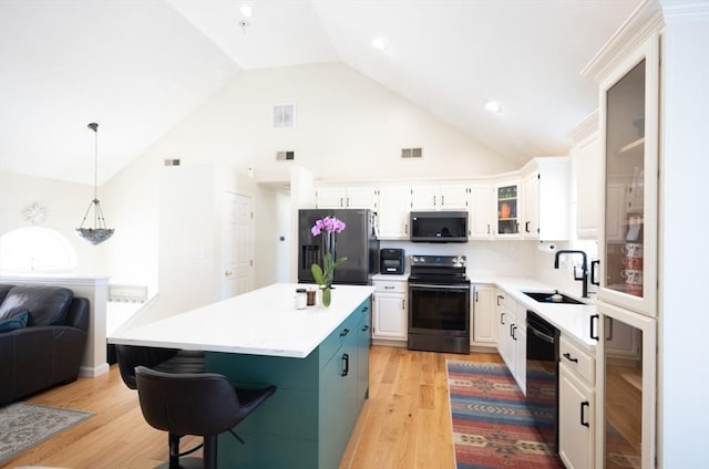 kitchen featuring visible vents, black appliances, light wood-style floors, white cabinetry, and a sink