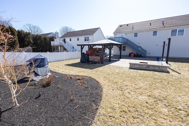 view of yard with a gazebo, a patio, a fenced backyard, and stairs