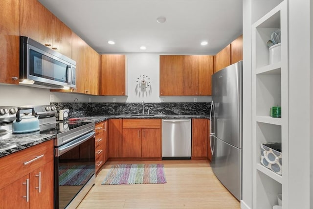 16 Miner St Unit 307, Boston, MA 02215 - kitchen featuring stainless steel appliances, dark stone counters, light wood-type flooring, a sink, and brown cabinets