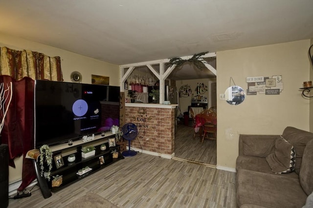 living room with indoor bar, a baseboard heating unit, and wood-type flooring