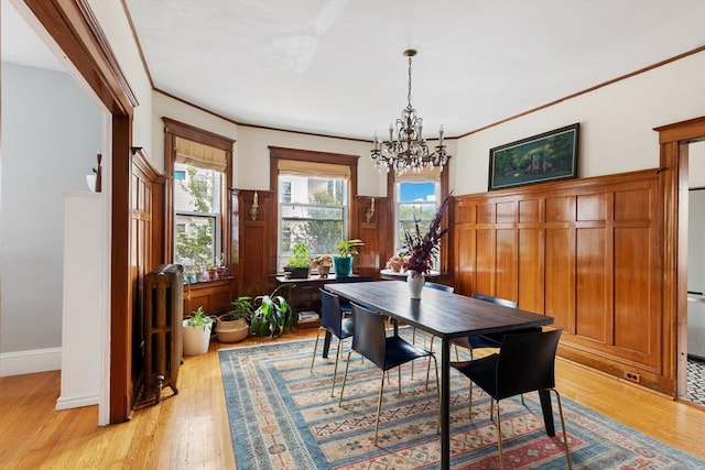 dining space featuring light hardwood / wood-style flooring, radiator, a chandelier, and ornamental molding