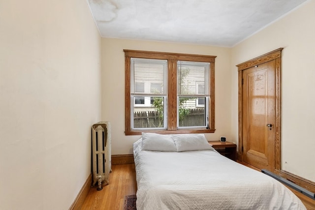 bedroom featuring radiator, crown molding, and light hardwood / wood-style floors