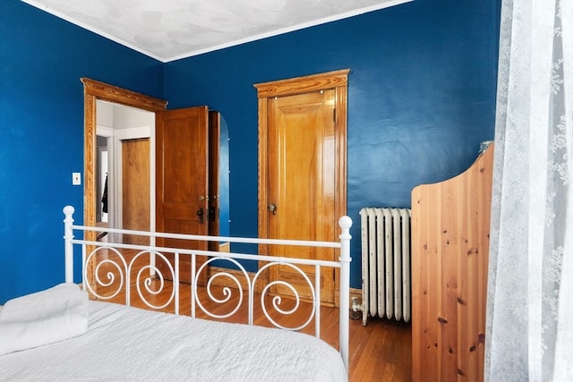 bedroom with radiator and hardwood / wood-style flooring