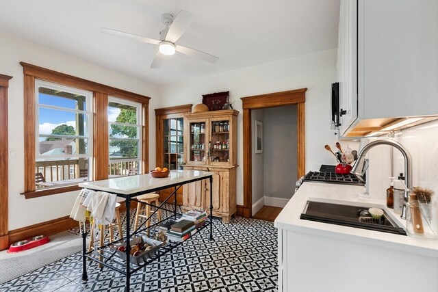 kitchen featuring wood-type flooring, sink, white cabinets, stainless steel stove, and ceiling fan