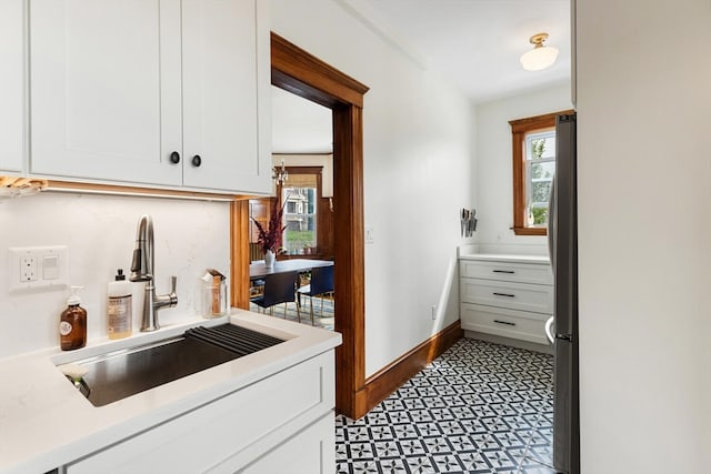 kitchen with white cabinets, stainless steel refrigerator, and sink