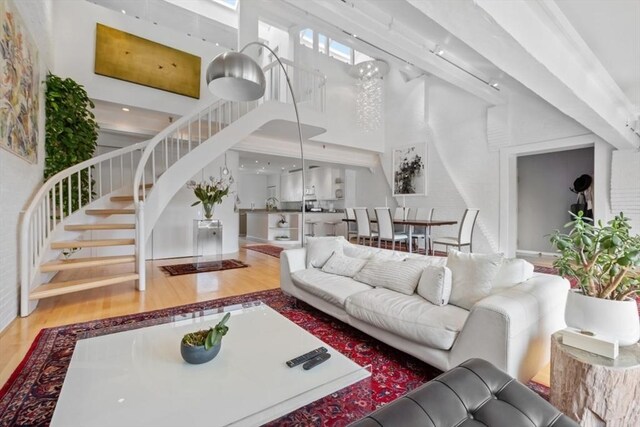 living room with a towering ceiling, hardwood / wood-style flooring, and track lighting